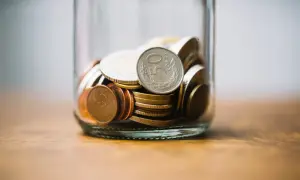 Słoik z monetami, w tym jedna z napisem "50 Groszy".